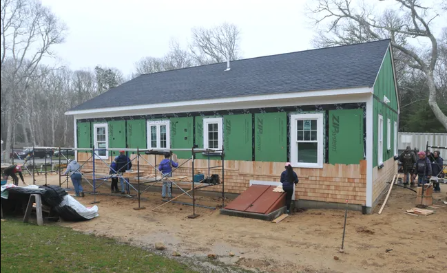 Image by Merrily Cassidy/Cape Cod Times; Volunteers shingle the back of the Veterans Build home at Phoebe Way in Brewster