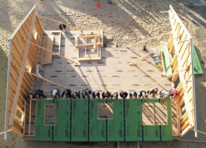 Aerial image of volunteers and future homeowners raising walls on a Habitat for Humanity of Cape Cod home on Old Kings Highway in Wellfleet.